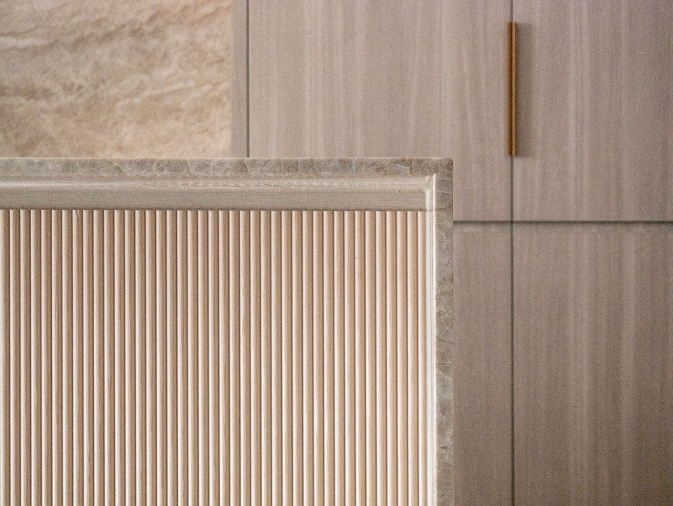 Stone edge meeting fluted timber and vertical grain joinery at Clara Residence