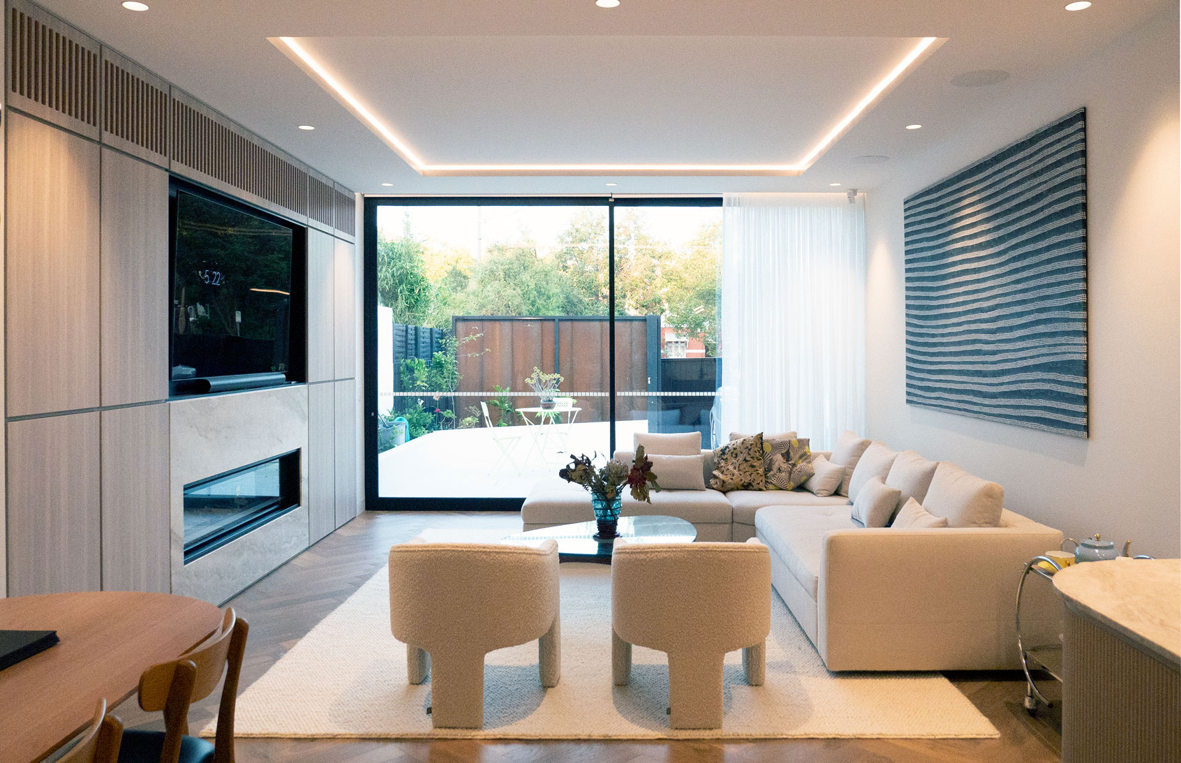 Family room with stone fireplace, integrated joinery, and sliding doors to the courtyard at Clara Residence