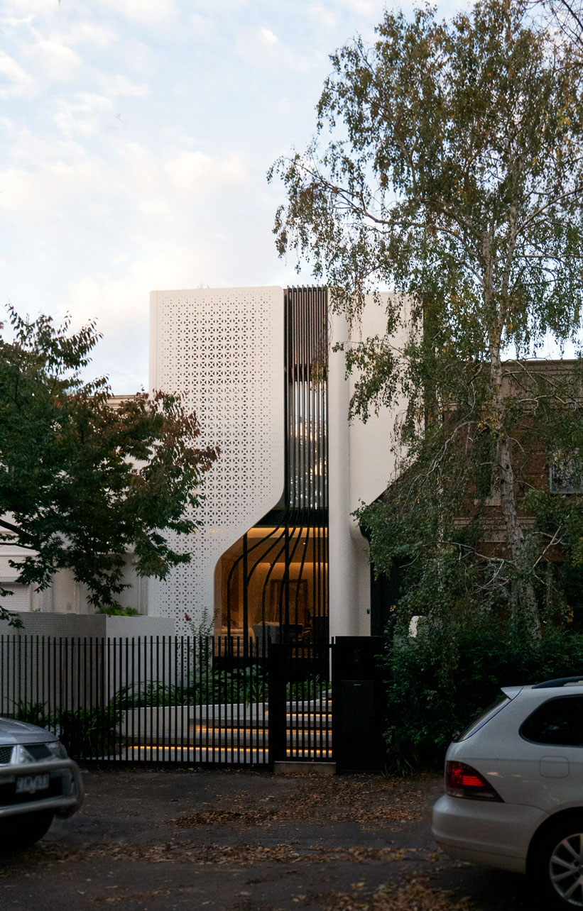 Clara Residence facade at dusk with perforated screen and curved glazing