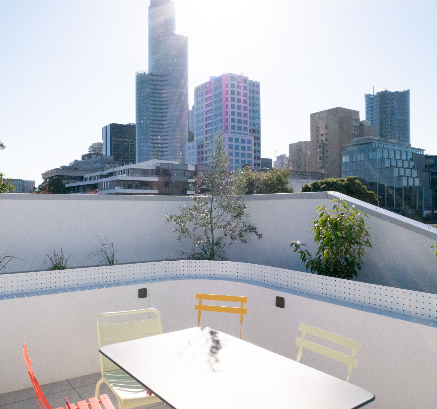 Rooftop terrace with curved perforated balustrade and Melbourne city skyline beyond at Clara Residence