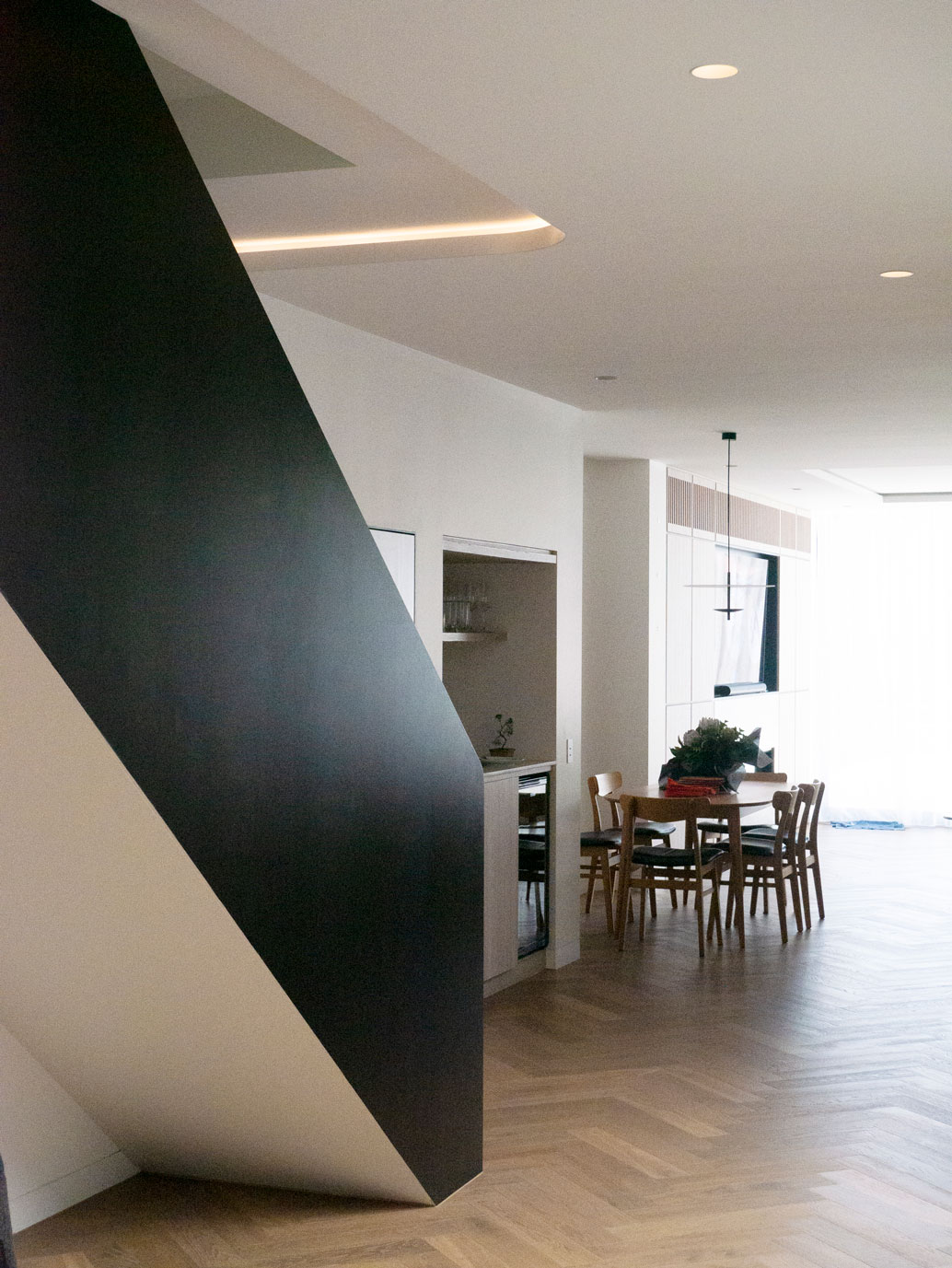 Faceted black stair volume rising through the open dining area at Clara Residence