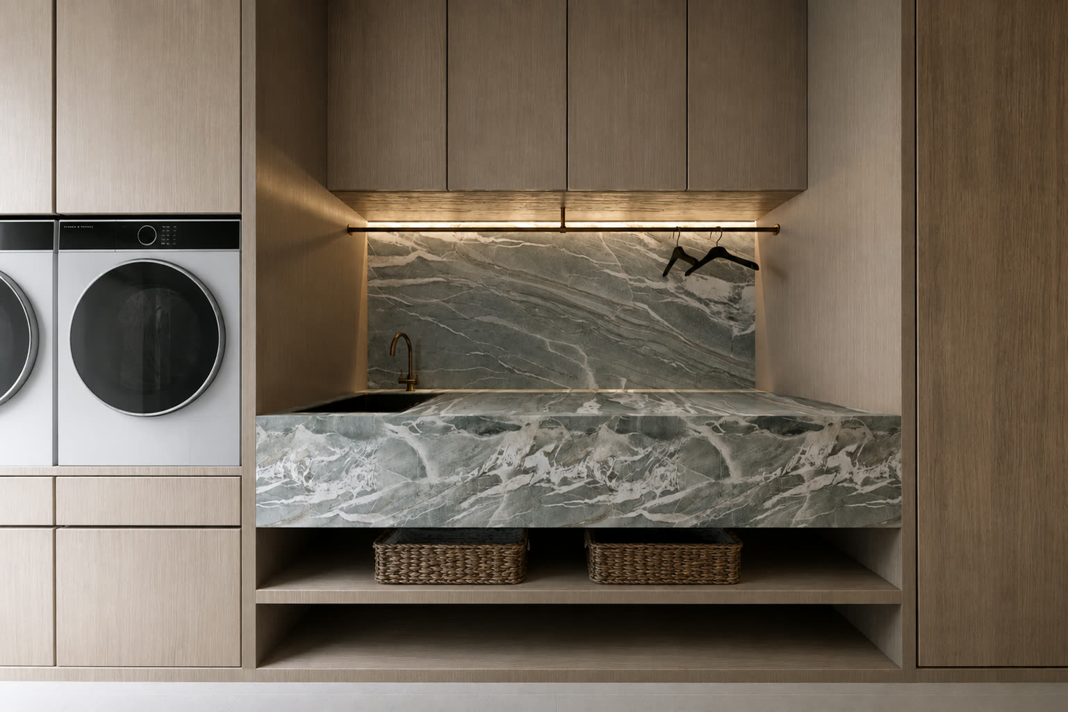 Contemporary laundry interior featuring green Tiffany stone benchtop and splashback with pale timber cabinetry.
