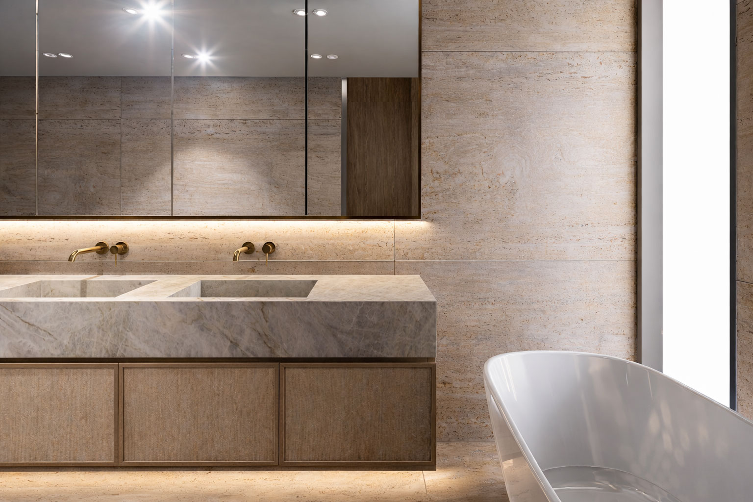 Travertine ensuite with concealed lighting and stone vanity